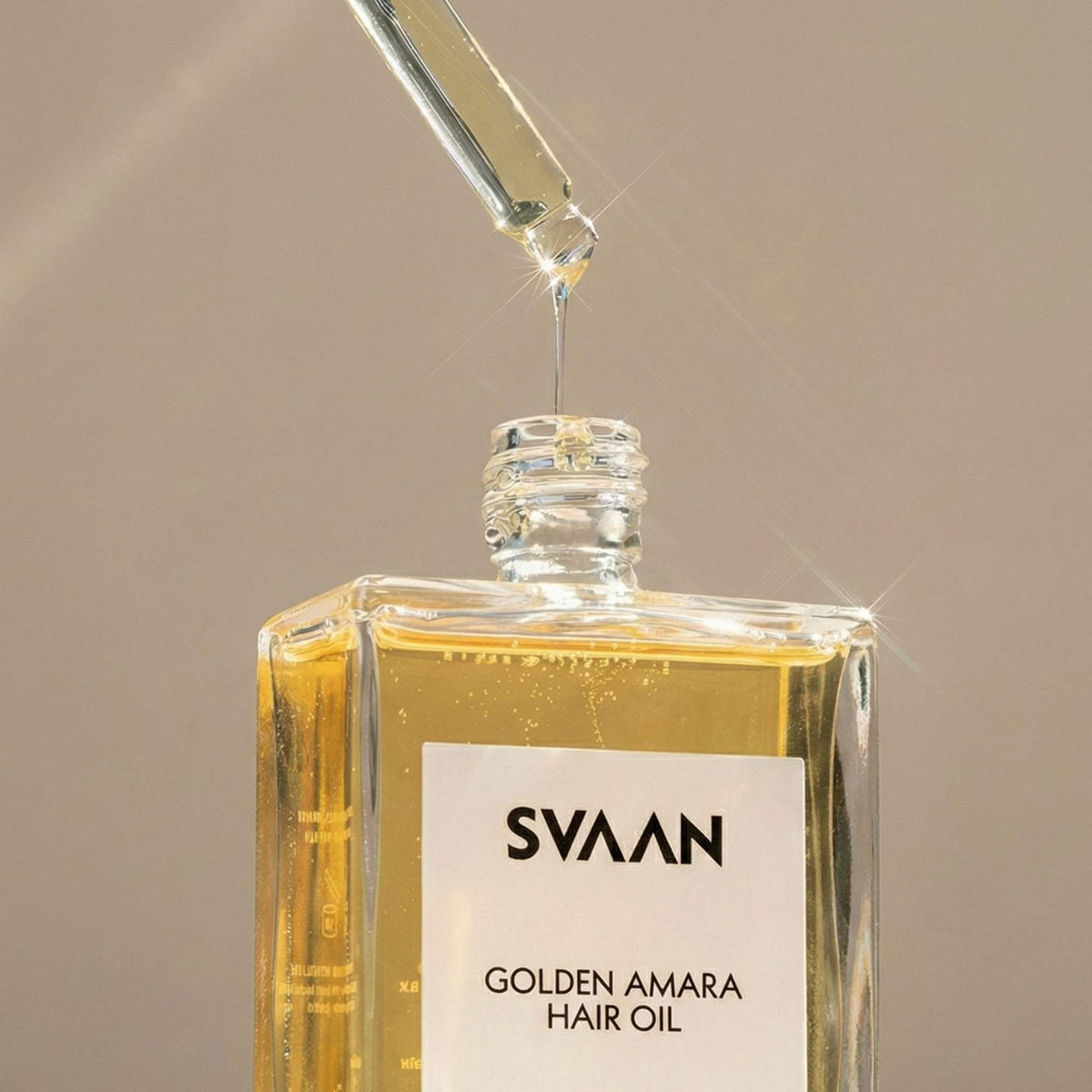 SVAAN Golden Amara Hair Oil with dropper on a beige background